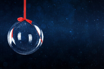 Christmas ball with red ribbon against dark background