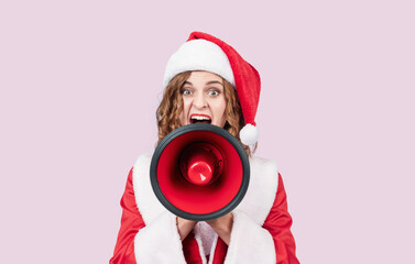 Excited woman in Santa costume shouting through red megaphone on pink background, holiday discount announcement, Christmas sale concept, festive advertising portrait.