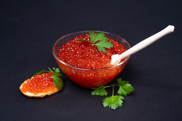 Exquisite red caviar in a glass bowl served with fresh parsley and a slice of bread. perfect for gourmet dining and culinary presentations.