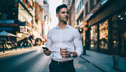 Fototapeta premium Confident Businessman Walking with Coffee and Phone on City Street