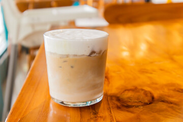 Iced coffee latte in a glass with milk on a blur cafe background. Summer refreshment concept. Front view.	