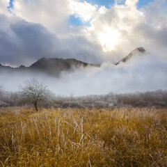 wide grass prairie among misty mountain valley  in light of sun