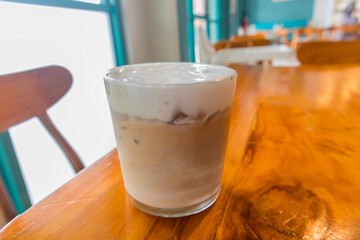 Iced coffee latte in a glass with milk on a blur cafe background. Summer refreshment concept. Front view.	