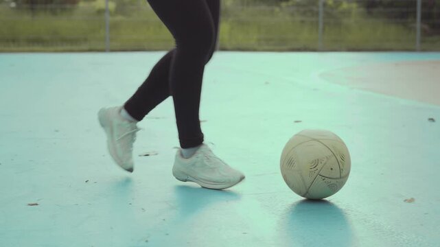 Asian girl playing futsal football outdoor.