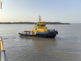 Fototapeta premium Tugboat with towline wound on winch drum assisting large vessel maneuvering during port operations. 5
