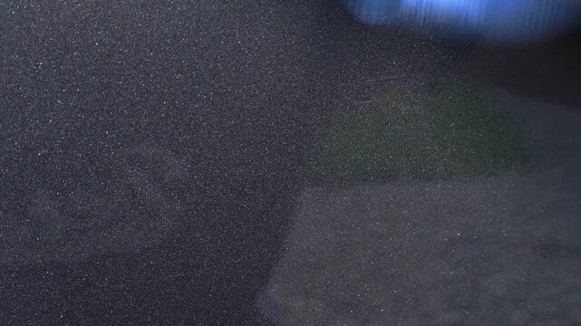Extreme close up buffing away polish residue from dark grey gar with blue microfibre towel