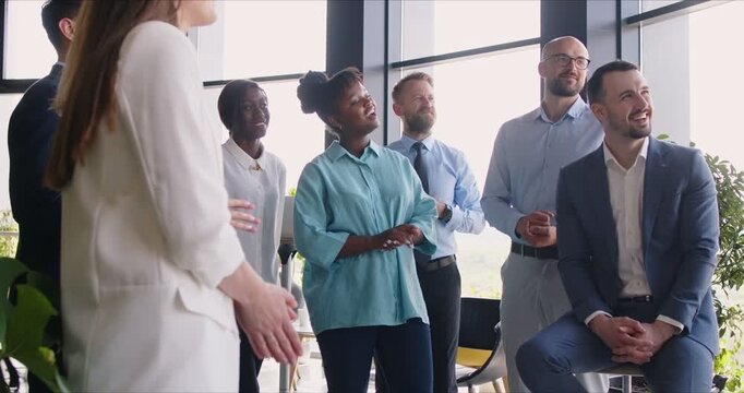 Happy satisfied diverse multinational office team of colleagues watching and listening presentation from business trainer, coach or senior executive at business conference or working meeting. - Powered by Adobe