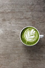 A cup of green tea matcha latte on wooden background                        
