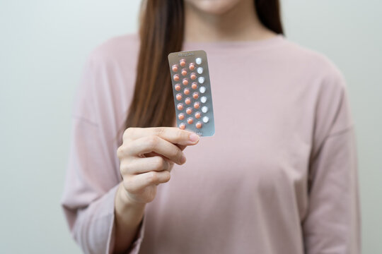 Contraception and pregnancy, menstruation concept, birth control pills asian young woman hand holding hormonal oral contraceptive medicine, take pharmaceutical to prevention, safe virus sex disease.