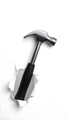 A hammer breaks through white paper, in a diagonal shot. Focus on the tool and torn paper edges