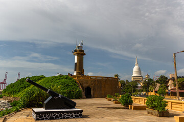 Colombo Lighthouse and the modern Sambodhi Chaithya stupa with a vintage cannon in the foreground at the Port of Colombo