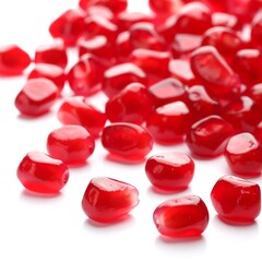 A pile of vibrant red pomegranate seeds scattered on a bright white surface, macro shot