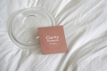 Square card with clarity protects simply text near clear circular lid on white sheet
