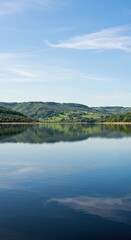 A vast expanse of tranquil reservoir water under a bright summer sky, reflecting verdant green hills and a clear distant horizon ,warm ,reservoir ,spacious