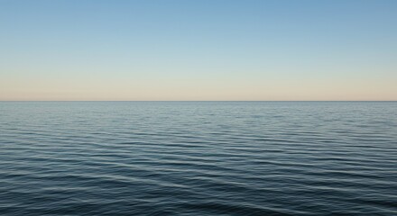 A vast expanse of tranquil water reflecting the soft light, extending towards the distant horizon beneath a clear, open sky. Serene view ,outdoor ,watersurface ,vast