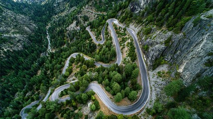 Spectacular aerial view of serpentine mountain pass winding through dense alpine forest landscape.