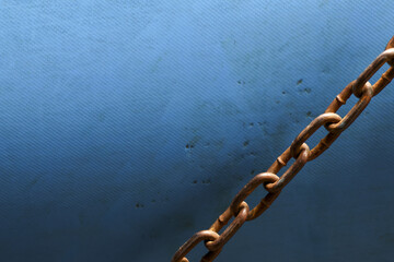 Strong rusty metal chain link against textured blue background. An industrial concept of strength,...