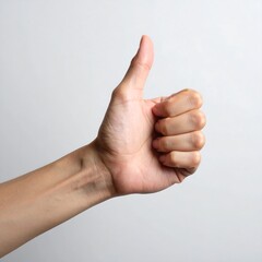 A hand with fair skin extending a thumb upward against a light, neutral backdrop in a simple shot