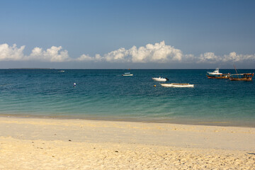 White sand beach with boats anchored in the turquoise water of the Indian Ocean, Zanzibar Tanzania