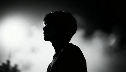 Monochrome silhouette of person looking to left against bright background