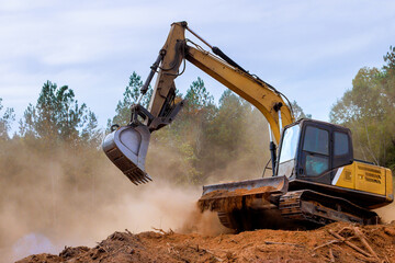 Heavy machinery is clearing trees dirt at construction site in forest, creating large dust cloud. © ungvar