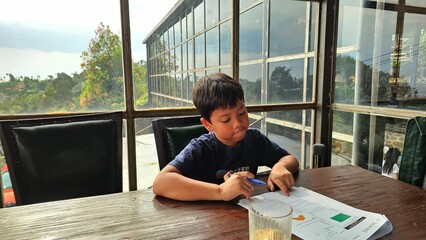 Asian boy is studying seriously. His dad teach him  doing  worksheet.