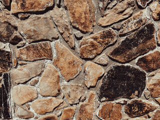 A close up view of a rustic stone wall shows irregularly shaped rocks with rough textures and earthy colors the natural pattern creates an organic background for architectural design