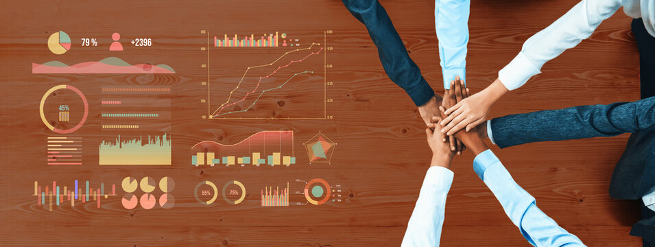 Diverse professionals collaborate around a table, placing hands together, with data visualizations illustrating success metrics and business analytics in a modern office environment. Axiom - Powered by Adobe