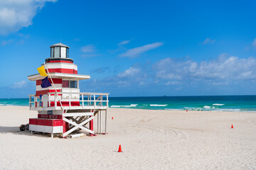 Fototapeta premium Lifeguard tower on the sandy Miami Beach shore. Iconic Art Deco lifeguard station under summer sky. Scenic view of South Beach coastline in Florida. Colorful lifeguard tower, symbol of Miami tourism.