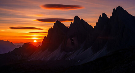 Dramatic sunset over the jagged peaks of the dolomites, with lenticular clouds adding to the scenic beauty and creating a breathtaking vista