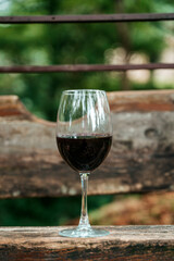 Glass of Red Wine on Wooden Bench in Summer Park