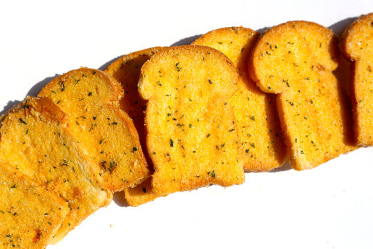 Crispy garlic bread slices on white background.