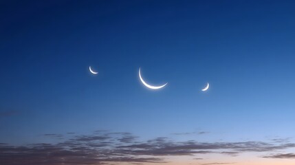 Three luminous crescent moons shine brightly in a deep blue twilight sky with delicate clouds near the horizon
