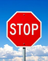 Obraz premium Close-up of a red, octagonal sign against a bright, cloudy sky