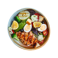 A delicious and healthy grilled chicken salad bowl filled with fresh vegetables hard boiled eggs and lemon slices presented from a top down perspective