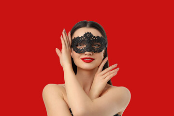 Woman poses with black lace mask on red backdrop