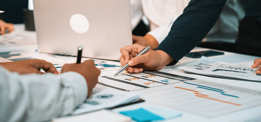 A dynamic business team collaborates during a strategy meeting, utilizing laptops and analyzing financial charts to plan future projects and enhance productivity. SACTR