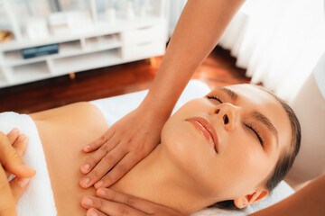 Caucasian woman customer enjoying relaxing anti-stress spa massage and pampering with beauty skin recreation leisure in day light ambient salon spa at luxury resort or hotel. Quiescent