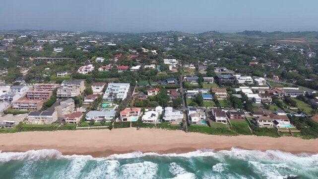 Ballito Coastal tourist town camera moving sideways along the beautiful beach, looking at the beachfront holiday accommodation on the North Coast, KwaZulu-Natal, South Africa Aerial 4K Video