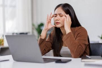 Sad and frustrated asian woman feeling tired and worried about a problem sitting at desk with...