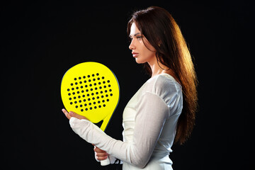 Female athlete poses with a yellow paddle in a dramatic studio setting for sports photography