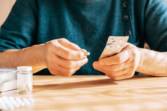 An elderly woman takes a large number of medications daily. Chronic disease treatment, aging, health problems, dementia and loneliness, home treatment, regular pill intake