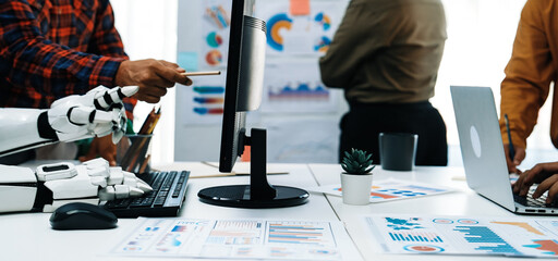A modern office scene featuring a robot aiding human workers during a business meeting. This image illustrates teamwork, technology, and productivity in a collaborative environment.Noogenesis