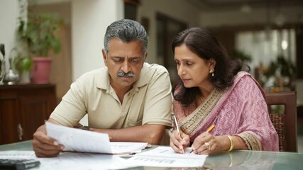 Focused Senior Indian Couple Reviewing Financial Documents and Budgeting at Home