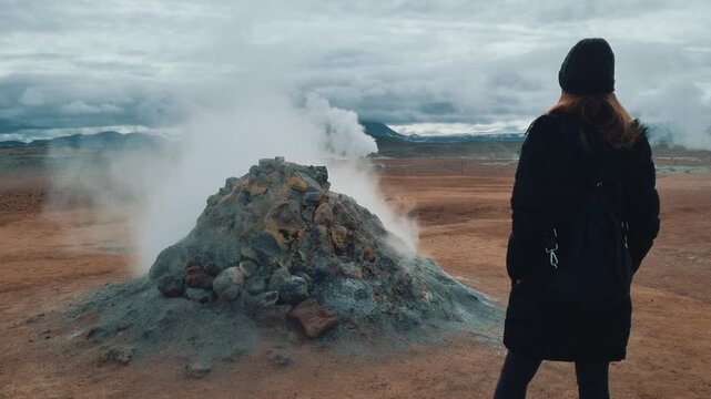 Traveler watching steam rising from a fumarole in a geothermal area in Iceland
