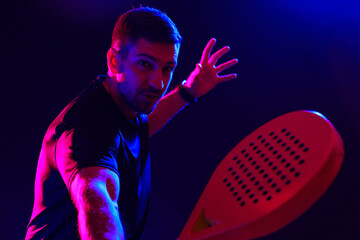 Man playing paddle sports in neon lighting during an indoor match