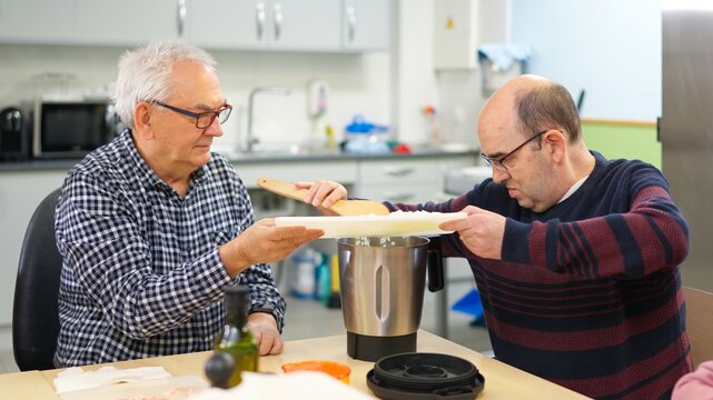 Two men with physical disability cooking in an inclusive kitchen - Powered by Adobe