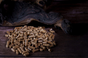 Wood pellets pile on a dark wooden surface with natural wood in the background, showing eco-friendly heating