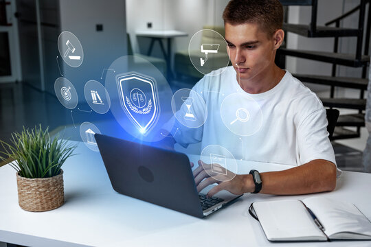 Young man using laptop with digital security icons in modern workspace