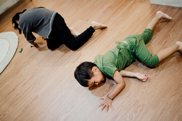 Two young children crawl and play on the floor during an energetic moment at home, showing natural...